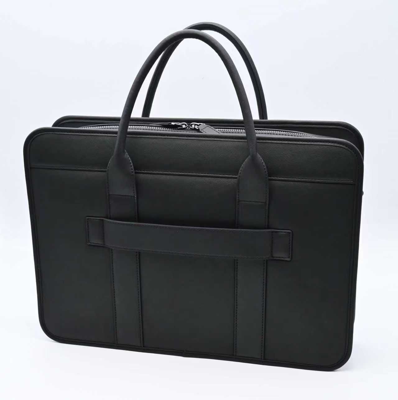 Black laptop bag shown from the back on a white background, with rounded top handles, a structured slim profile, and a horizontal back strap for travel or daily work use.