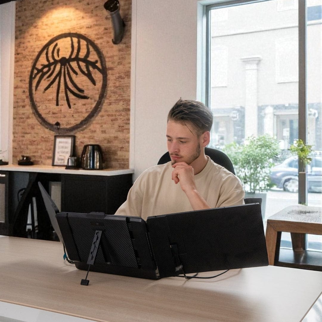 Professional working at a desk using a triple screen portable monitor setup with two external displays attached to a laptop for enhanced productivity