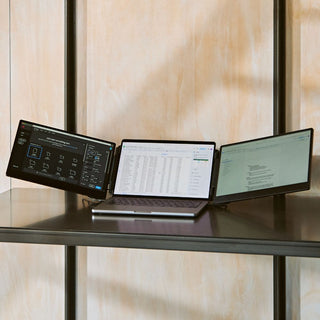 Portable monitor triple-screen setup on a metal shelf, showing a laptop with two angled side displays for multitasking across design, spreadsheets, and documents.