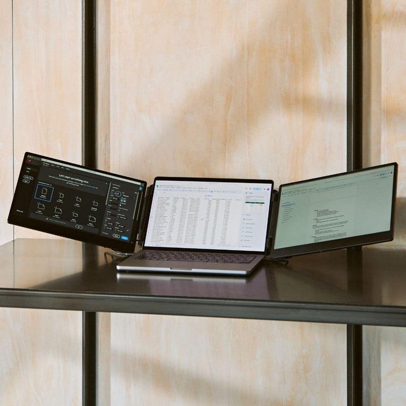 Portable monitor triple-screen setup on a metal shelf, showing a laptop with two angled side displays for multitasking across design, spreadsheets, and documents.