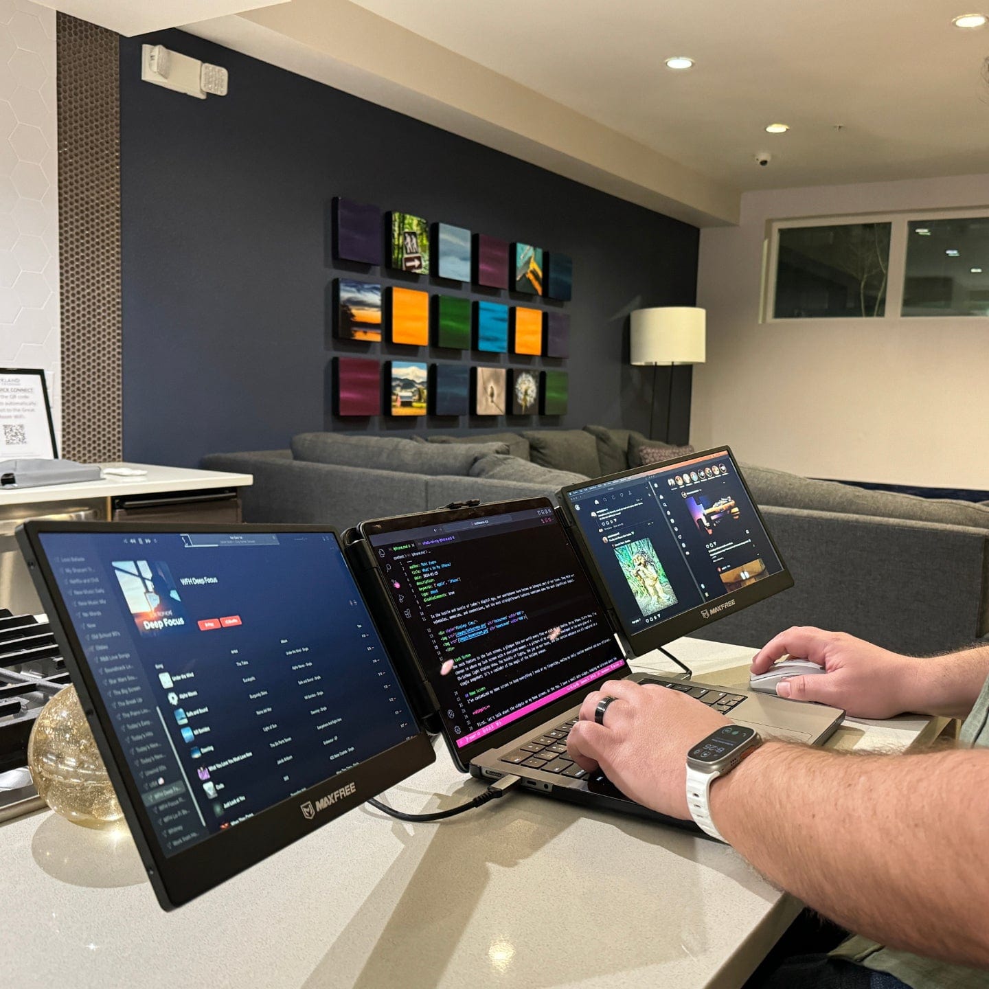 Triple screen portable monitor connected to a laptop displaying coding, dashboards, and applications across three screens for improved workflow efficiency