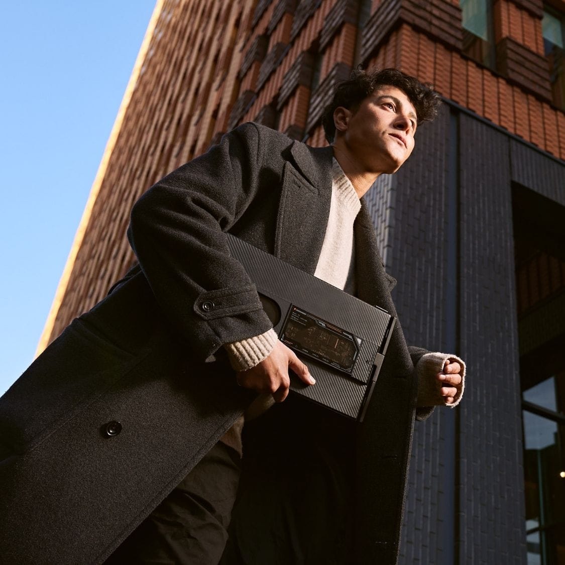 Person carrying a folded portable monitor outdoors, demonstrating its compact design for commuting, travel and mobile work.