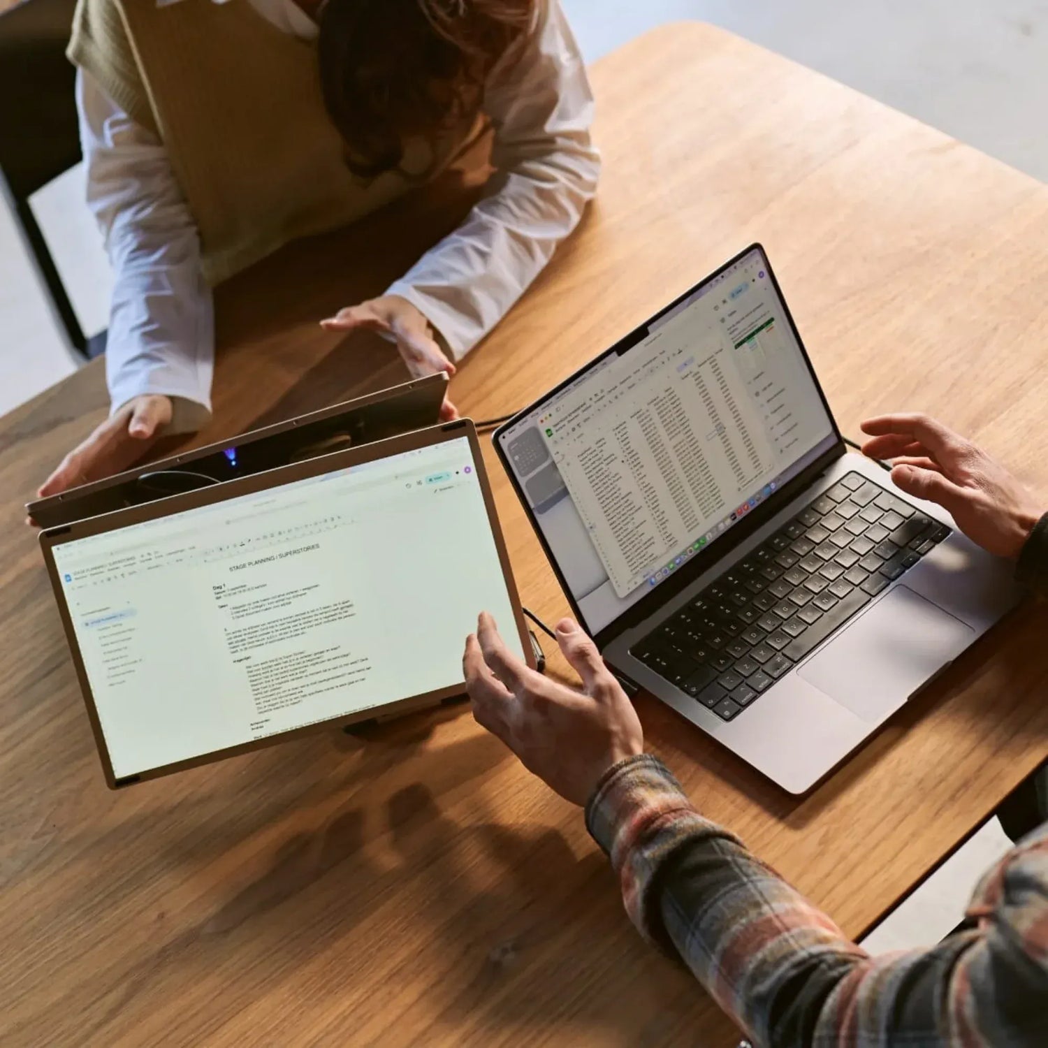 Portable monitor used for collaboration at a wooden table, with an extra screen turned toward a colleague while the laptop displays a spreadsheet.