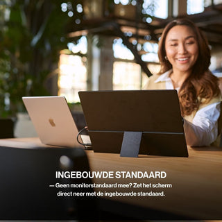 OneSight AMOLED portable monitor positioned beside a laptop using its integrated kickstand, allowing the screen to stand securely without a separate monitor stand.