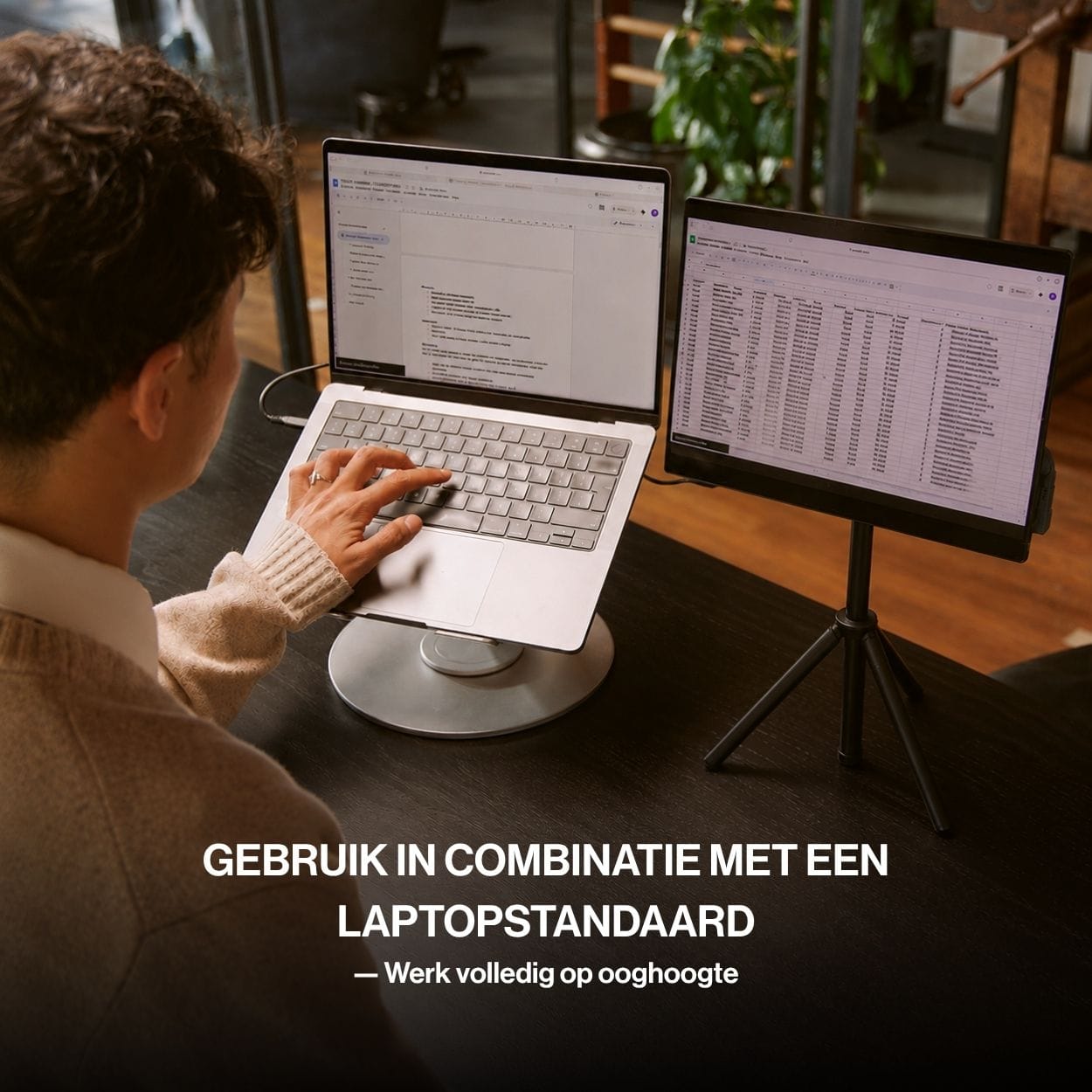 Person working with a laptop on an ergonomic stand beside a OneSight AMOLED portable monitor on a tripod, creating a comfortable eye-level dual-screen workstation.